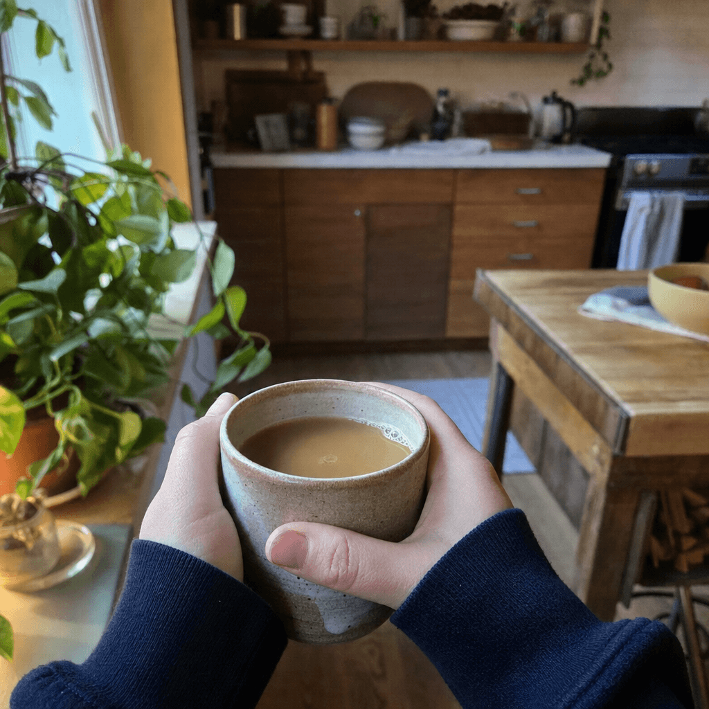 Daniel holding a ceramic mug of Meridian coffee at home